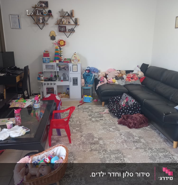 חדר מגורים עם צעצועים מפוזרים וספה שחורה